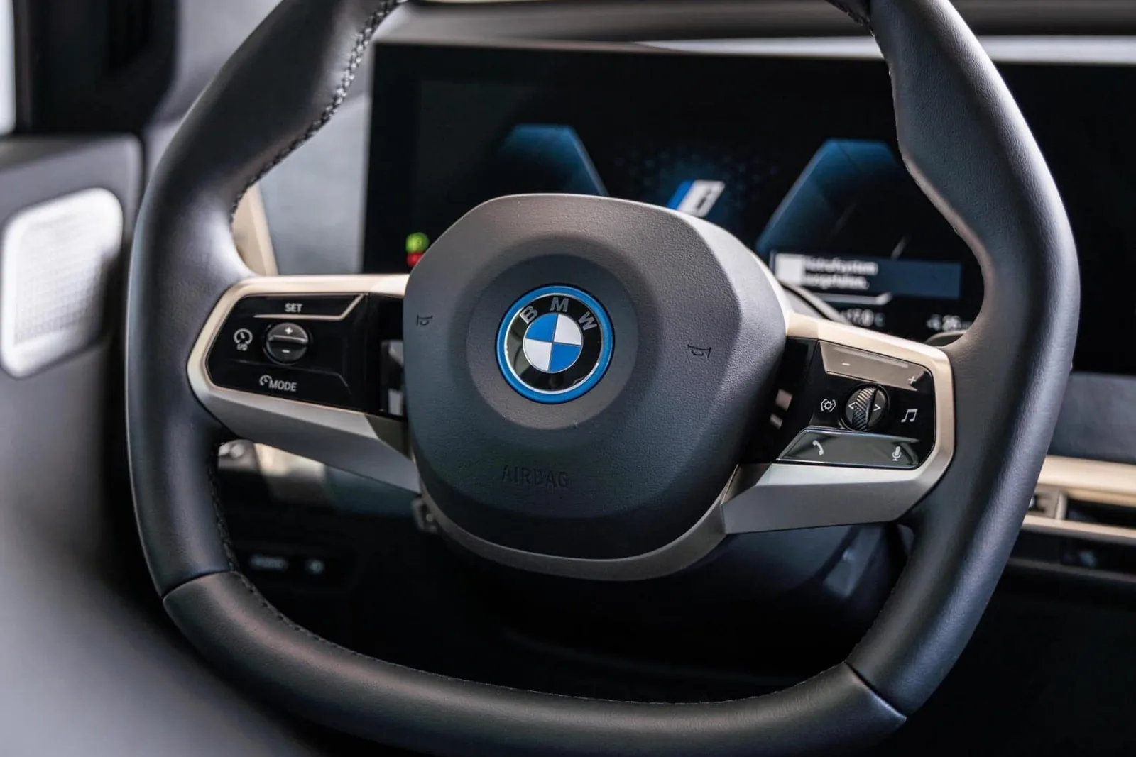 BMW iX cockpit: leather steering wheel and the curved driver display